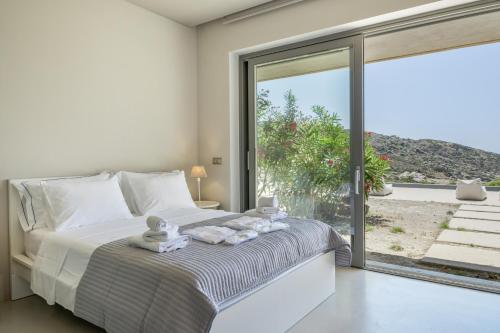 a bedroom with a bed and a large window at Aetos Cave Villa With Sunset in Mylopotas
