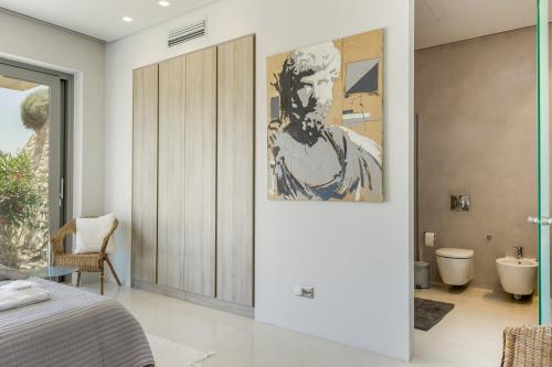 a bedroom with a painting of a man on the wall at Aetos Cave Villa With Sunset in Mylopotas