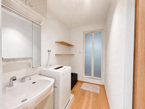a white bathroom with a sink and a washing machine at 晴の松 in Wakayama