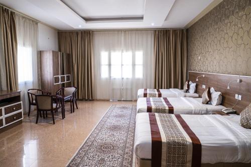 a hotel room with two beds and a table at Al Diyar Hotel in Nizwa