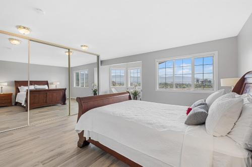 a white bedroom with a bed and a mirror at KnoxPeace BnB in Kelowna