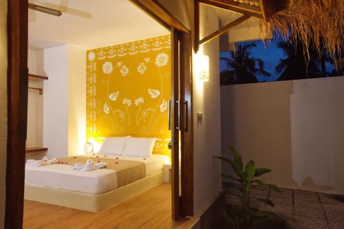 Un dormitorio con una cama con una pared amarilla. en Golden Villa, en Gili Trawangan