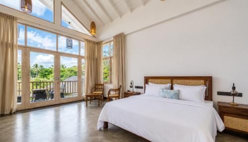 a bedroom with a large bed and a balcony at The Oceans Edge in Dodanduwa