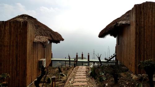 a path between two huts with the ocean in the background at Sapa Clay House - Mountain Retreat in Sa Pa