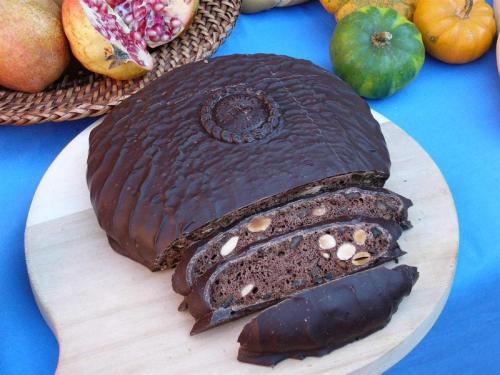 a chocolate cake on a wooden plate on a table at Palazzo Spada - Attico con terrazza vista fiume in centro in Codigoro