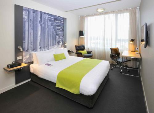 a hotel room with a large bed and a desk at Mercure Melbourne Therry Street in Melbourne