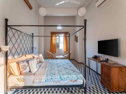 a bedroom with a bed and a flat screen tv at DanCenter Kolpol by CheckIn Udaipur in Udaipur