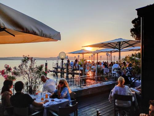 a group of people sitting at tables at a restaurant with the sunset at Hotel Pace in Sirmione
