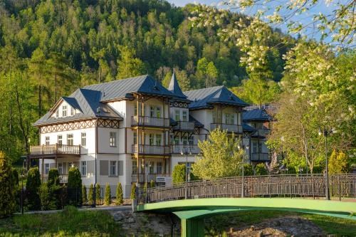 a large house on a bridge over a river at Wanda Luxury Boutique Hotel - tylko dla dorosłych in Szczawnica