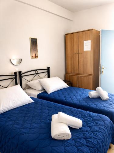 two beds in a room with blue sheets and white pillows at Crystal Kimolos in Kimolos