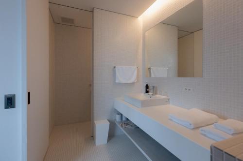 a white bathroom with a sink and a mirror at Experience Ise Miyamachi Hotel in Ise
