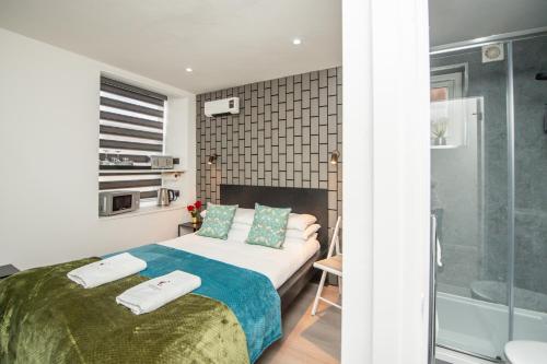 a bedroom with a bed and a bathroom with a shower at The Belmont Suits in Liverpool