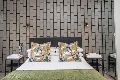 a bedroom with a bed with pillows and a wall at The Belmont Suits in Liverpool