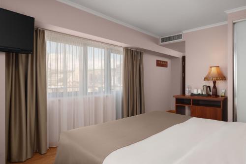 a bedroom with a large white bed and a window at Ani Plaza Hotel in Yerevan