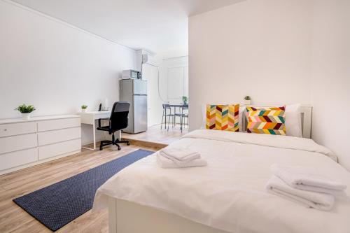 a white bedroom with a large bed and a desk at Deda Studio w. Smart TV · AC · washing machine in Bucharest