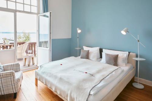 a bedroom with a large white bed and a balcony at Lieblingsplatz Hotel Strandperle in Travemünde