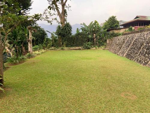 a large field of grass next to a stone wall at Hotel Kay Terrace in Campaka