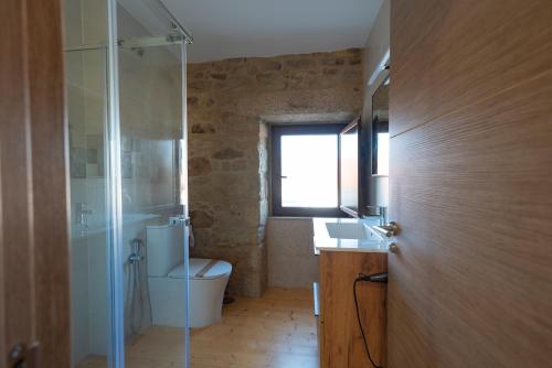 a bathroom with a toilet and a glass shower at Casa Ataraxia II in Boiro