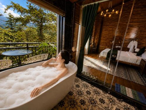 a woman sitting in a bath tub in a room at Cloud Chaser Hotel in Sapa