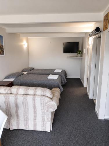 a hotel room with four beds and a couch at The Cave Motel in Levin