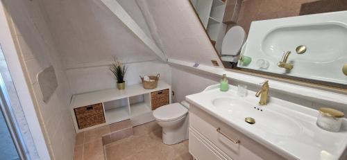 a white bathroom with a sink and a toilet at La Romantique du Château in Gaillan-en-Médoc