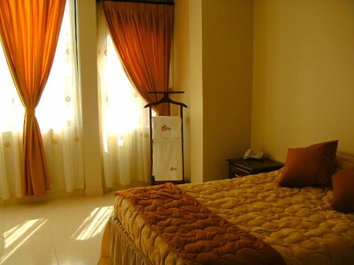 a bedroom with a bed with orange curtains and a window at Hostal Fevilamir in Ibarra