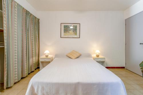 a bedroom with a white bed with two night stands at Studio meublé in Saint-Rémy-de-Provence