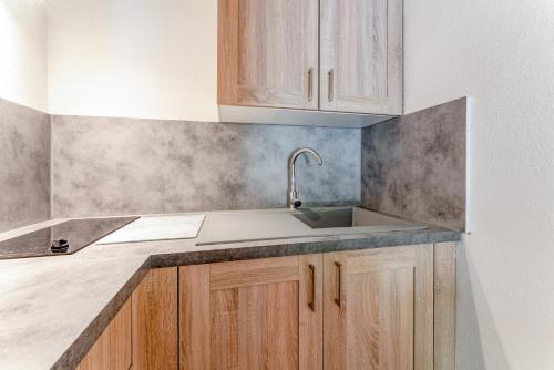 a kitchen with a sink and wooden cabinets at Studio meublé in Saint-Rémy-de-Provence