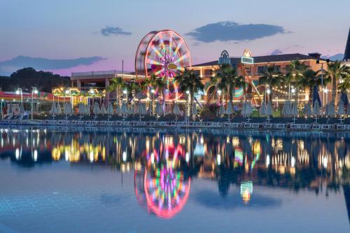 a roller coaster and a ferris wheel at night at Granada Luxury Belek - Family Kids Concept in Belek