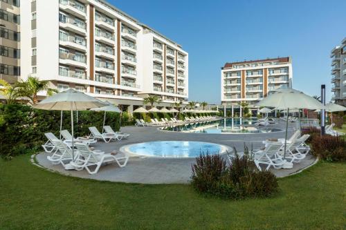a patio with chairs and umbrellas and a pool at Greenwood Suites Resort in Lara