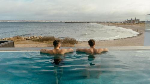 two men sitting in a swimming pool next to the beach at Marienlyst Strandhotel in Helsingør