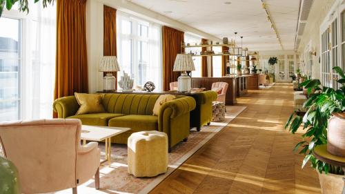 a lobby with a green couch and tables and chairs at Marienlyst Strandhotel in Helsingør