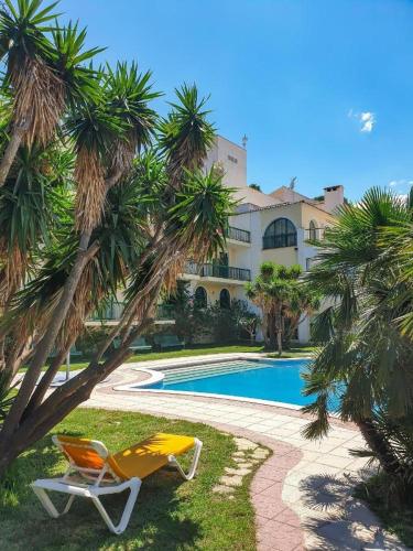 a yellow chair sitting next to a pool with palm trees at ALEGRIA Pino Alto in Miami Platja