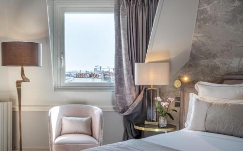 a bedroom with a bed and a chair and a window at Hôtel Elysia by Inwood Hotels in Paris