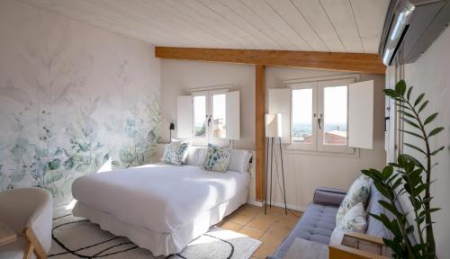 a bedroom with a white bed and a blue couch at Hotel Boutique Niu de Sol - Designed for Adults in Palau-Saverdera