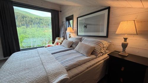 a bedroom with a large bed with a large window at Bergnes Lodge in Senja