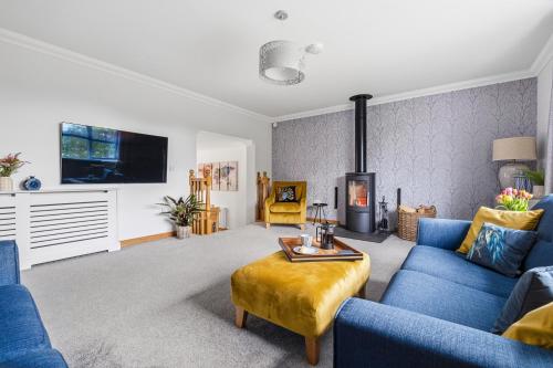 a living room with blue couches and a fireplace at Glenisla, Aviemore, fantastic location with sauna and hot tub in Aviemore