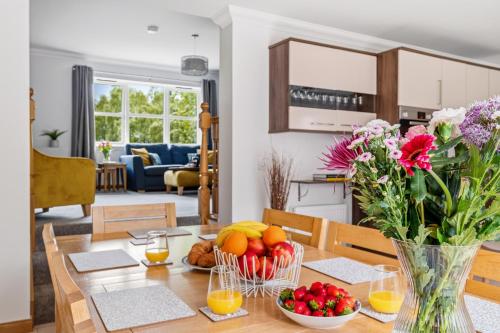 a dining room table with fruit and flowers in a vase at Glenisla, Aviemore, fantastic location with sauna and hot tub in Aviemore