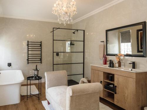 a bathroom with a sink and a chair and a mirror at Fiore Guest Accommodation in Greyton