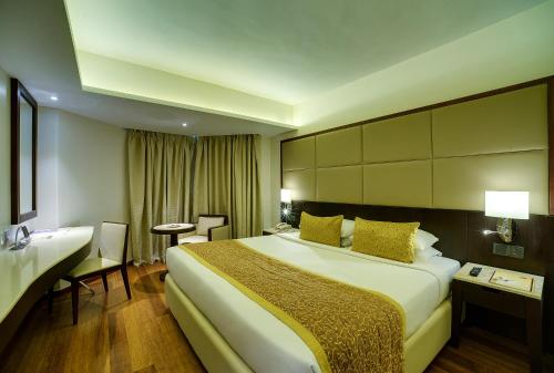 a hotel room with a large bed and a desk at Ramee Guestline Hotel Juhu in Mumbai