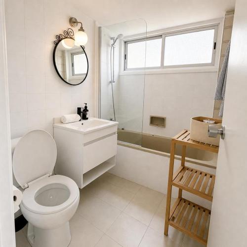 a bathroom with a toilet and a sink and a mirror at 2BR Seafront Apt in center with community pool in Larnaca