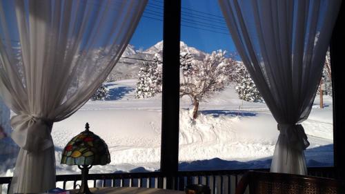 a view of a snow covered mountain from a window at Hotel Tae Windsor in Myoko
