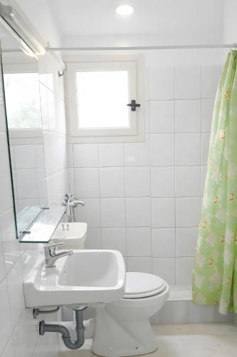 a bathroom with a toilet and a sink and a window at Studio Gouvia Kitchenette Pool 8 in Gouvia