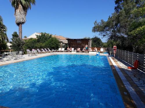 a large blue swimming pool with people sitting around it at Studio Gouvia Kitchenette Pool 5 in Gouvia