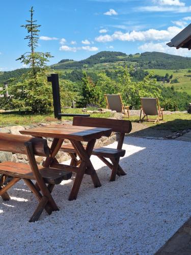a picnic table and chairs with a view of the mountains at Planinska kuća Radulović in Goč