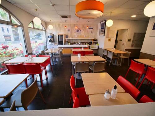 a restaurant with wooden tables and red chairs at ibis budget Blois Centre in Blois