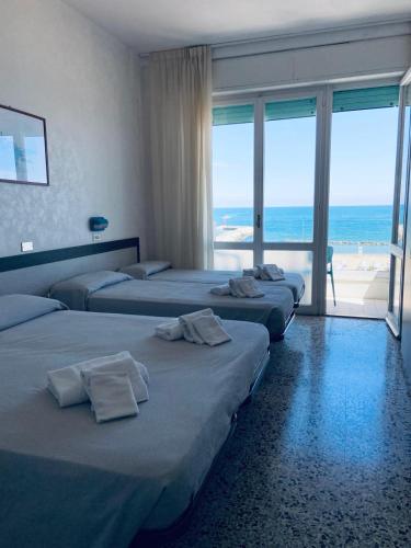 three beds in a room with a view of the ocean at Hotel Europa in Gabicce Mare