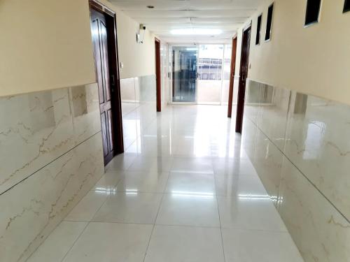 a hallway with white marble walls and a hallway with doors at Hotel Royal Park in Mangalore