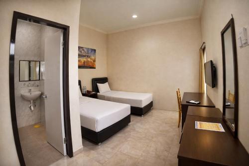 a hotel room with two beds and a sink at Mahkota Hotel in Genteng-kulon