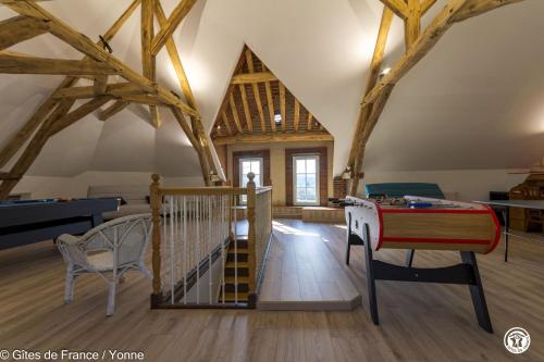 a room with wooden beams and a staircase and a table at Maison du Cosmos in Thorigny-sur-Oreuse